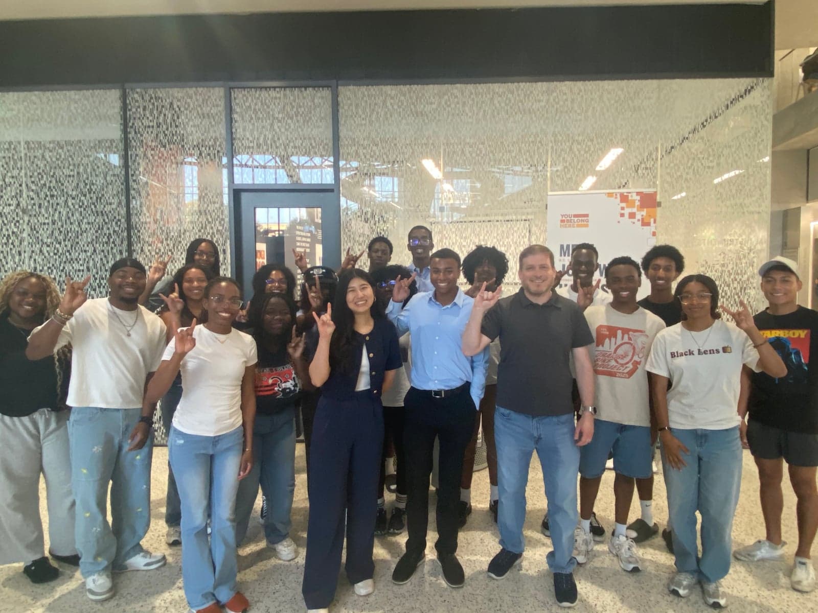 Texas NSBE members gathered at Finnegan lunch, many showing Hook 'em Horns with a You Belong Here banner