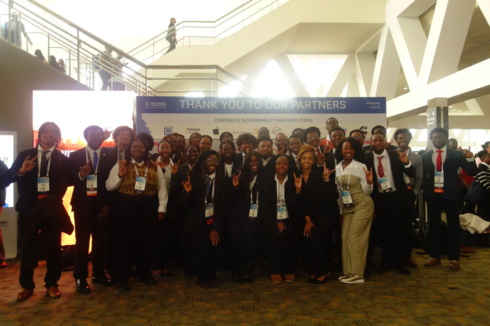 The full Texas NSBE delegation in business attire in front of a convention partners banner
