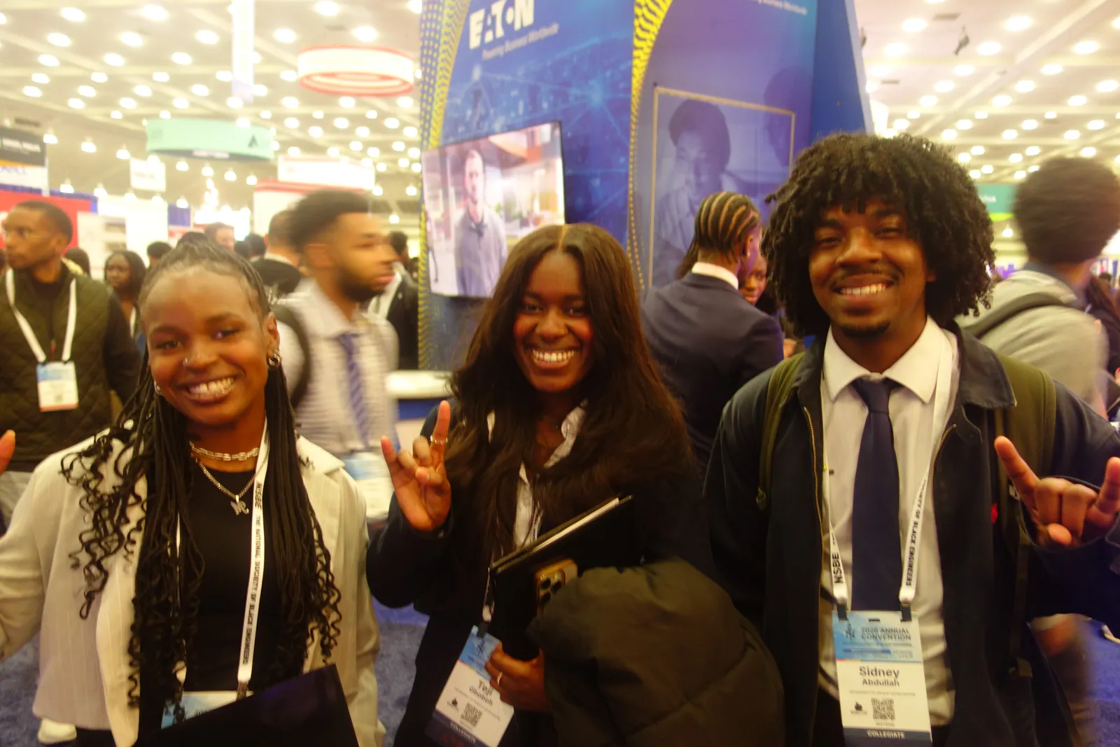 Three NSBE members in business attire smiling on the convention career fair floor