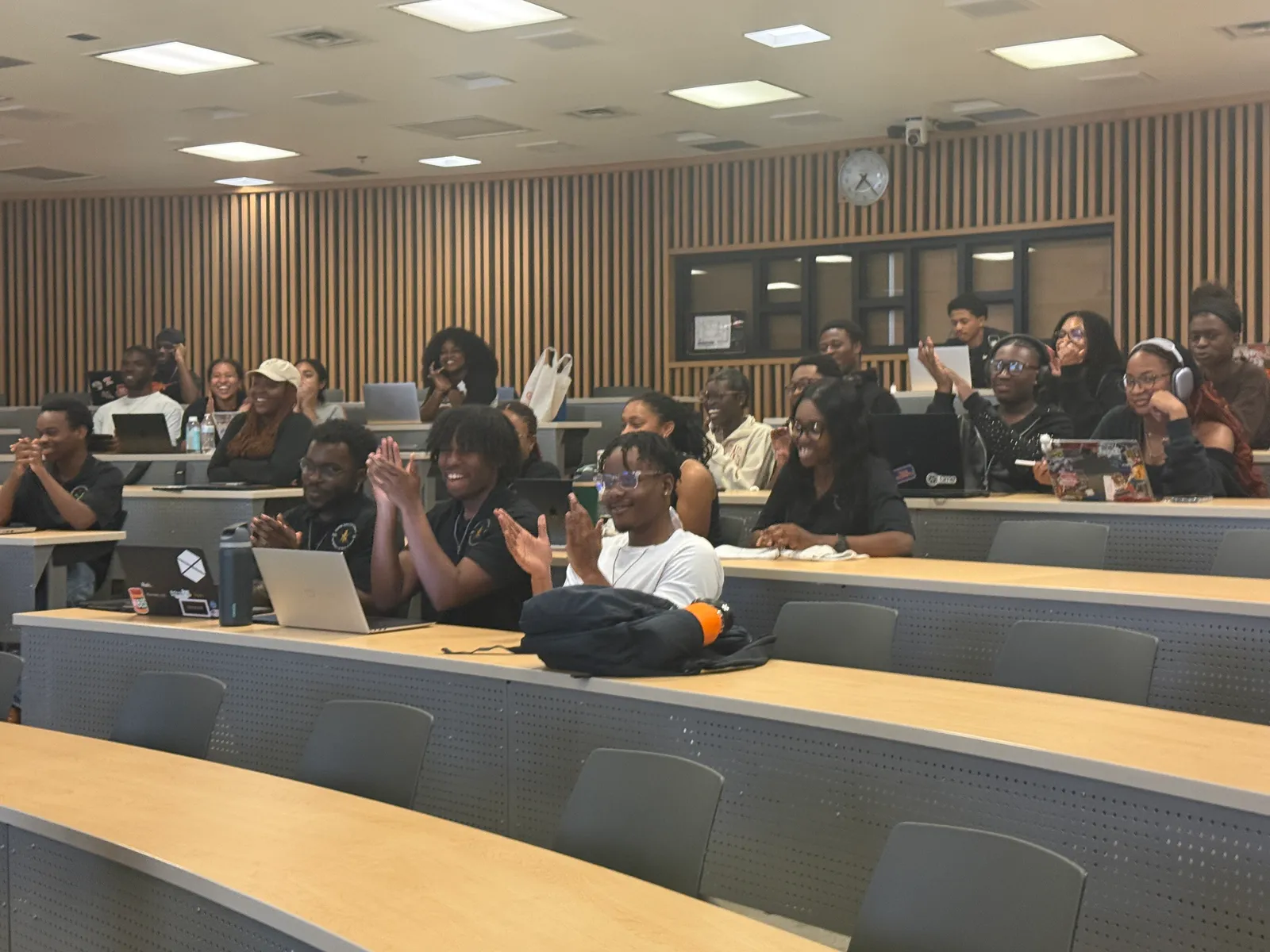 A packed lecture hall of NSBE members applauding at a spring general body meeting